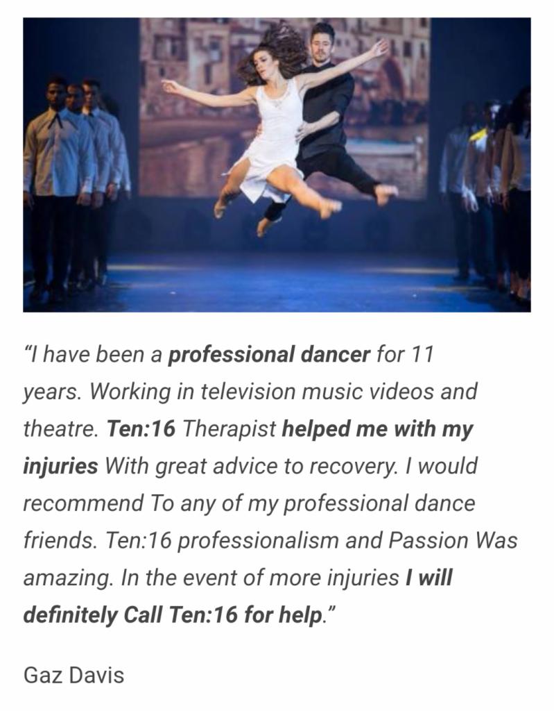 Tancerka w białej sukience w powietrzu, podtrzymywana przez tancerza w czarnym stroju na scenie podczas występu tanecznego, w tle zespół tancerzy i dekoracja.