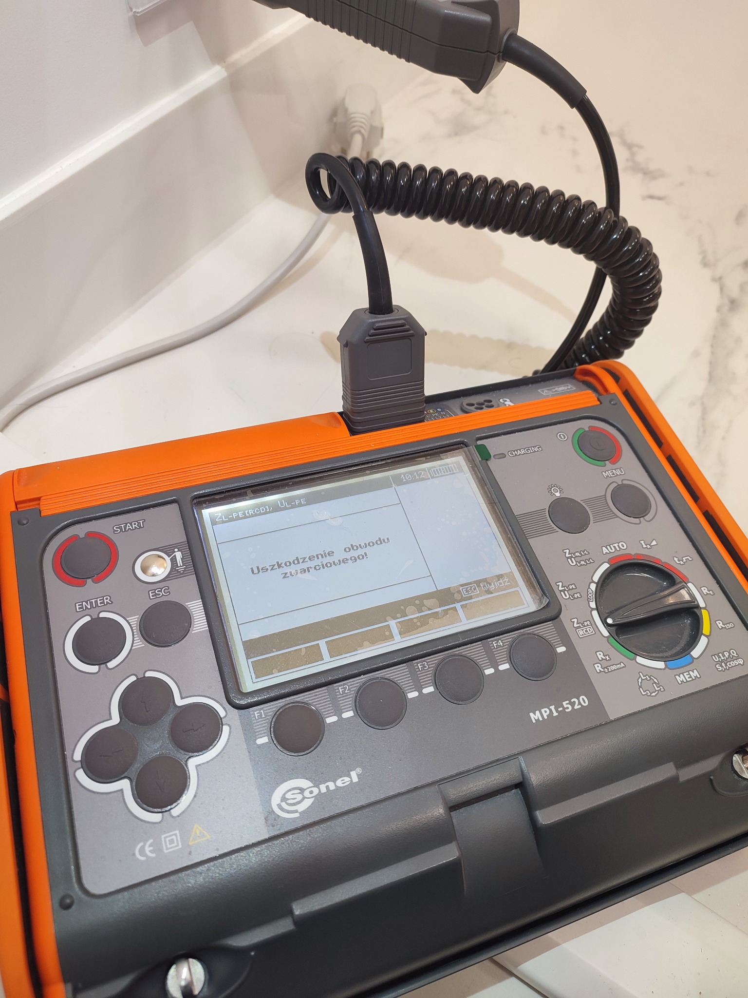 Pomarańczowo-szary miernik elektryczny Sonel MPI-520 z podłączonym przewodem pomiarowym, wyświetlający komunikat o uszkodzeniu obwodu zwarciowego.