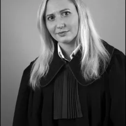 Portret kobiety z blond włosami, ubranej w togę z plisowanym żabotem, na szarym tle.