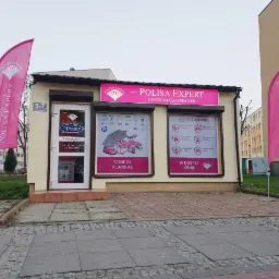 Fasada budynku Centrum Ubezpieczeń Polisa Expert z różowymi flagami reklamowymi po bokach, widoczny adres 5-7 i godziny otwarcia.