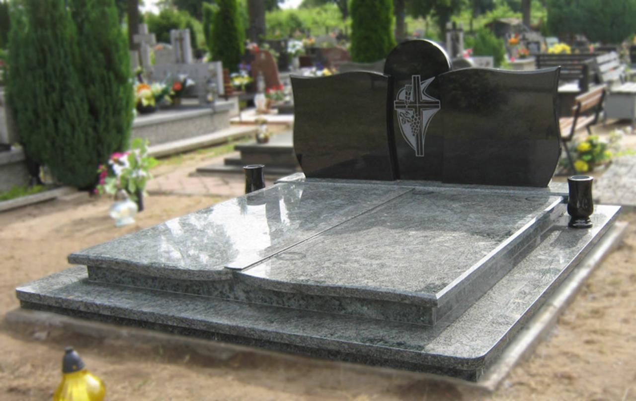 Dwukomorowy, granitowy pomnik z ciemną płytą nagrobną, zdobioną motywem krzyża i winogron, na cmentarzu z widocznymi innymi nagrobkami i zielenią.