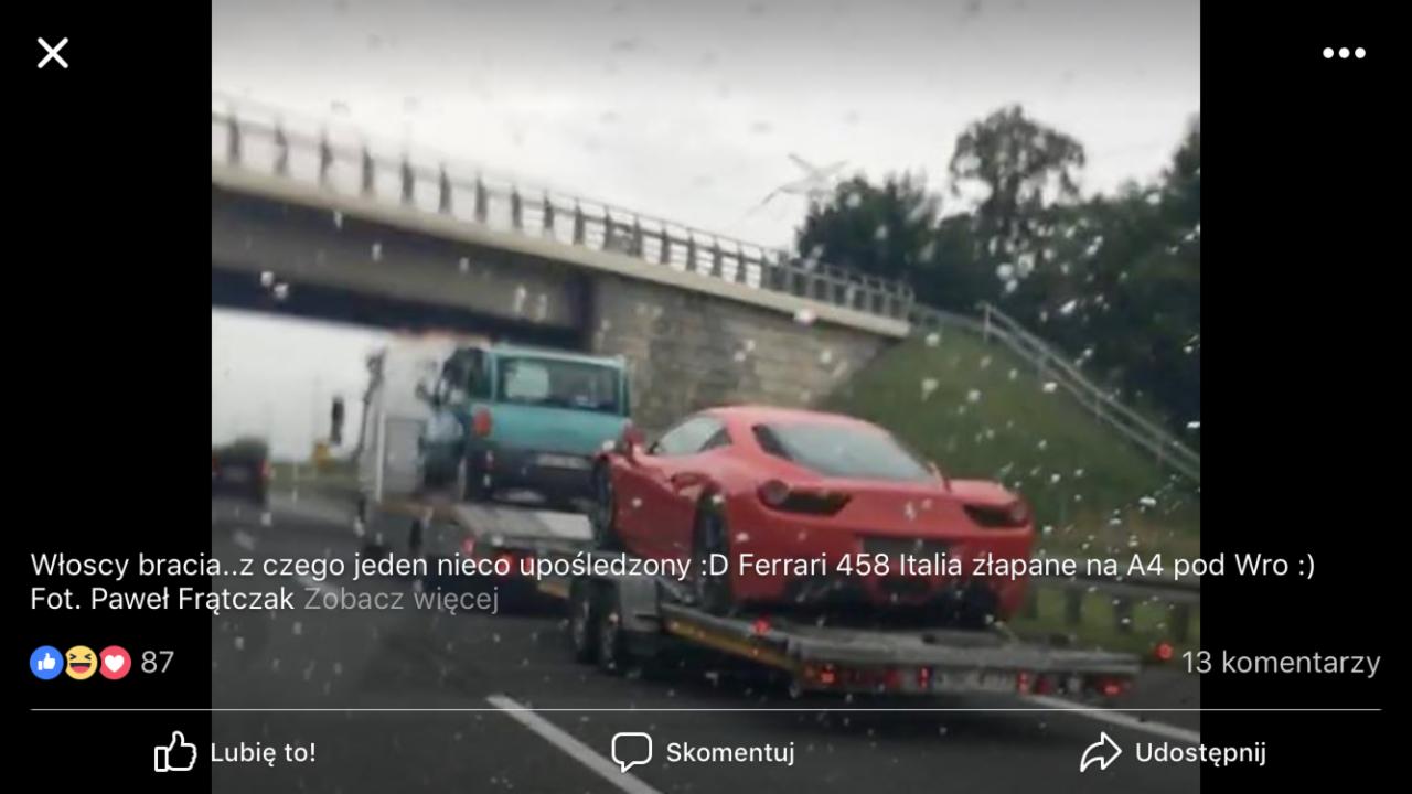 Czerwone Ferrari 458 Italia przewożone na lawecie pod wiaduktem autostradą A4 w deszczowy dzień.