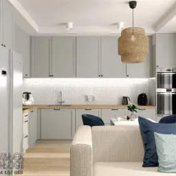 Jasnoszara kuchnia z drewnianym blatem i białymi heksagonalnymi płytkami, widok z salonu z beżową sofą i niebieskimi poduszkami, nowoczesna lampa wisząca z rafii.