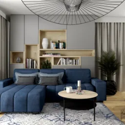 Wizualizacja salonu z niebieską sofą narożną, okrągłym stolikiem kawowym, regałem z półkami i dekoracjami, widokiem na ogród przez okno oraz nowoczesną lampą sufitową.