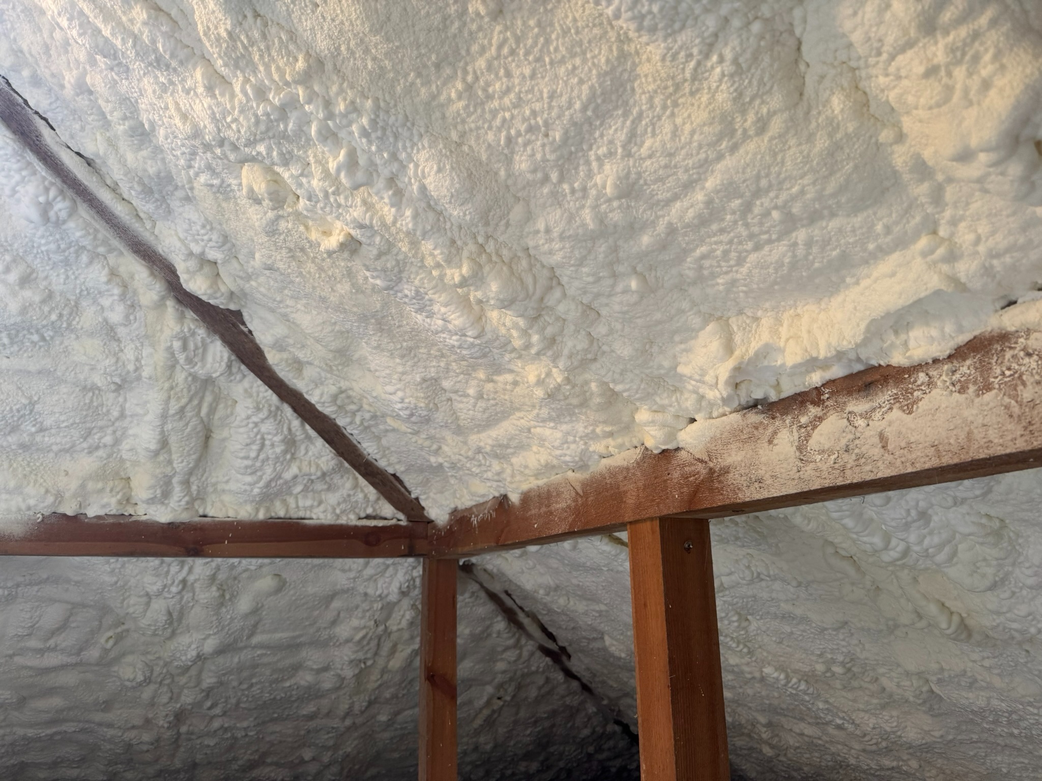 Poddasze ocieplone pianką PUR w Grodzisku Mazowieckim. Widoczne drewniane elementy konstrukcyjne i równomiernie nałożona warstwa izolacji.