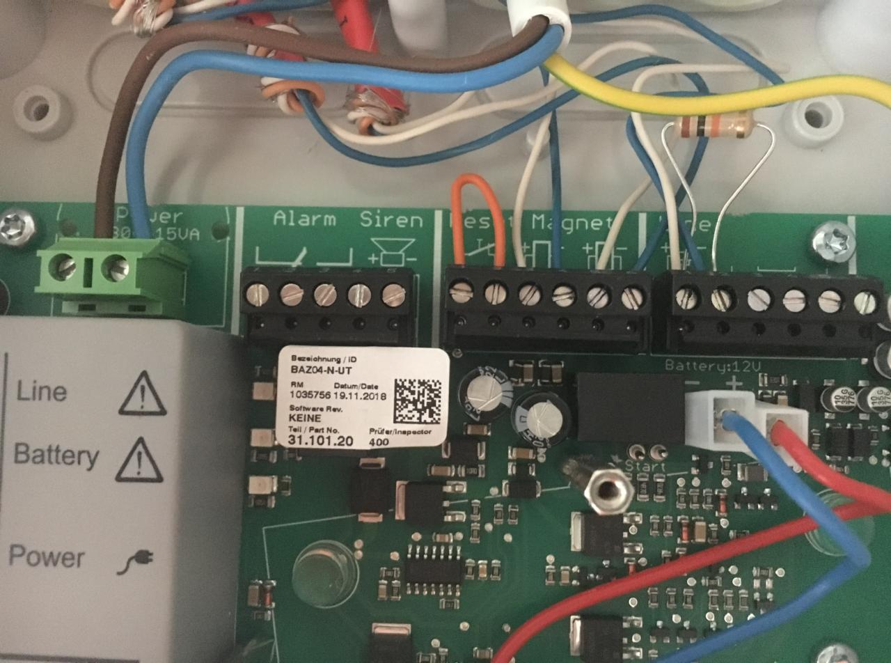 Podłączenia przewodów do płyty głównej centrali alarmowej BAZ04-N-UT z widocznymi terminalami Alarm, Siren, Magnet, Line, Battery i elementami elektronicznymi.