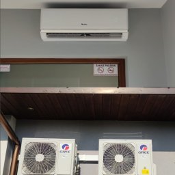 BIO - KLIM - Zewnętrzne i wewnętrzne jednostki klimatyzacji Gree zamontowane na szarej ścianie budynku, widoczny znak zakazu palenia w tle.