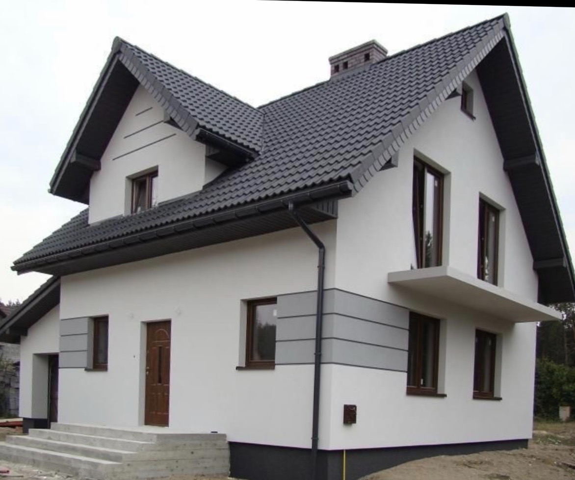 Biały dom z ciemnoszarą dachówką, elewacją z szarymi akcentami i brązowymi oknami, widok z zewnątrz z betonowymi schodami wejściowymi.