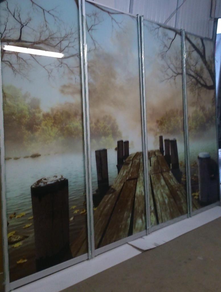 Szafa przesuwna z nadrukiem krajobrazu: drewniany pomost nad jeziorem w jesiennej mgle, widoczne metalowe ramy.