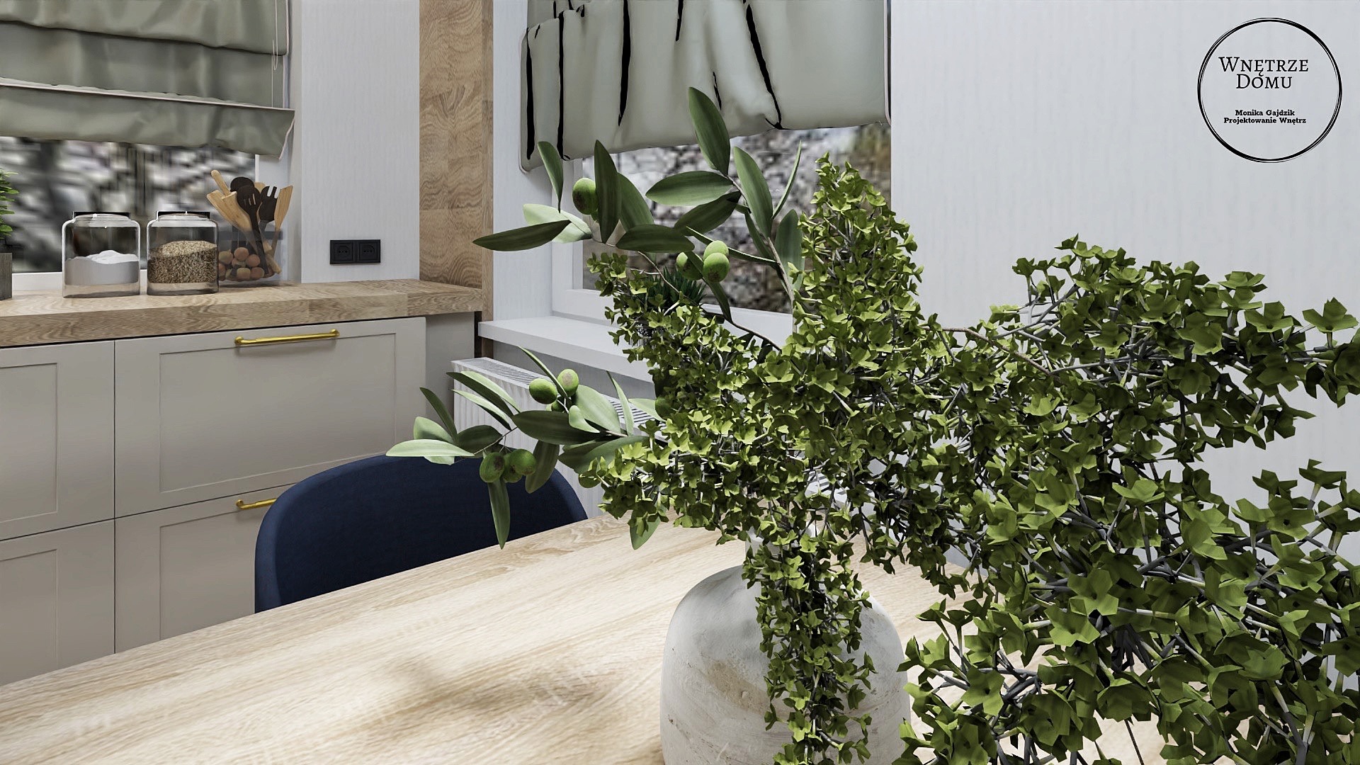 Wnętrze kuchni z blatem i szafkami w odcieniach szarości, złotymi uchwytami, drewnianym blatem, na którym stoi wazon z zielonymi gałązkami oliwnymi, w tle okno z roletą rzymską i logo firmy...