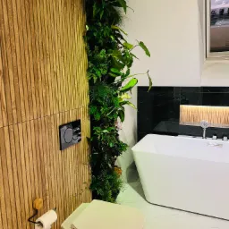 Nowoczesna łazienka z drewnianą ścianą, pionowym ogrodem, podwieszaną toaletą i wolnostojącą wanną.