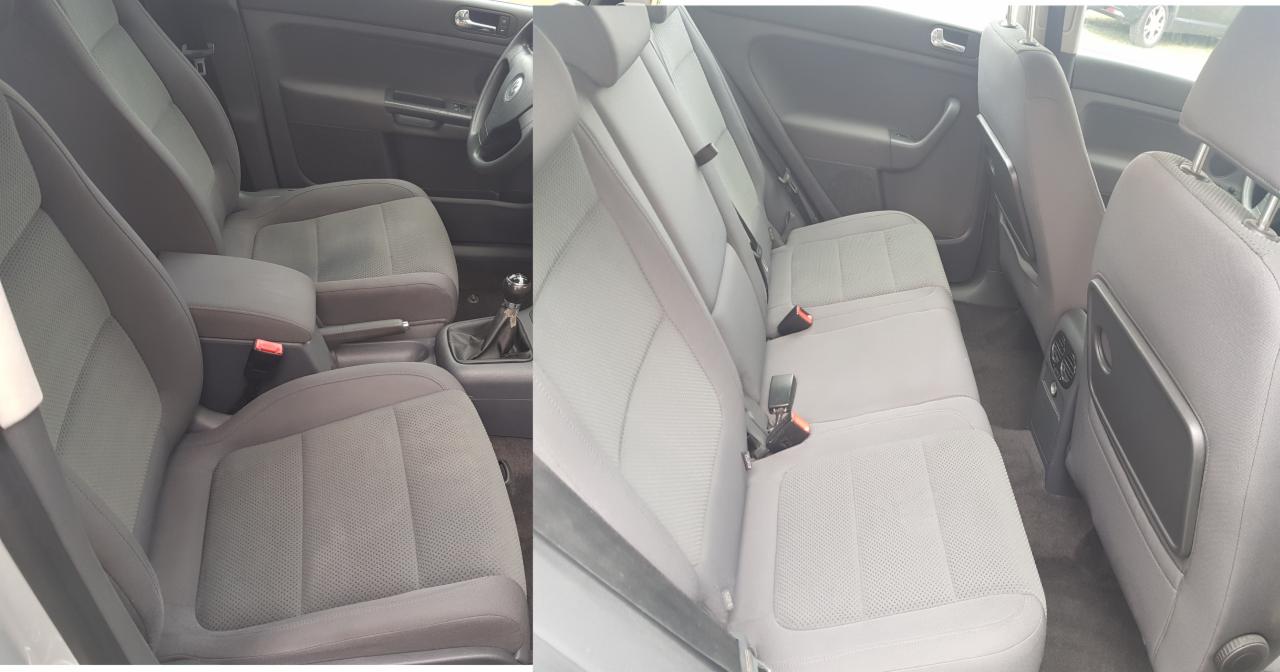 Wnętrze samochodu z szarą tapicerką, widoczne przednie fotele z podłokietnikiem oraz tylna kanapa z rozkładanymi stolikami przymocowanymi do oparć przednich foteli.