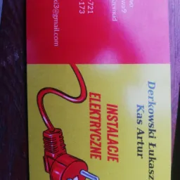 Wizytówka firmy elektrycznej z czerwonym rysunkiem wtyczki na żółtym tle, zawierająca dane kontaktowe: adres, numery telefonów i adres e-mail.