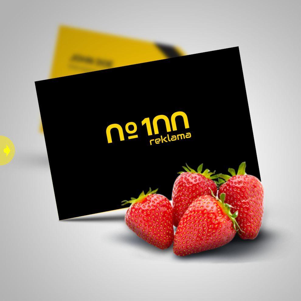 Czarna wizytówka z żółtym logo 'Nr 100 reklama' ułożona ukośnie na szarym tle z czterema truskawkami na pierwszym planie.