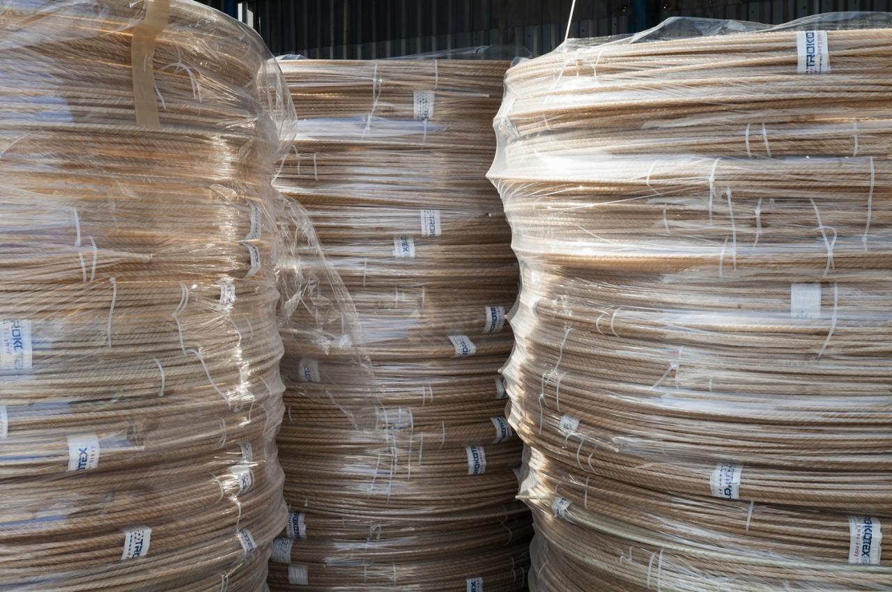 Sztaple brązowych prętów kompozytowych z włókna szklanego, owiniętych folią, z etykietami producenta.