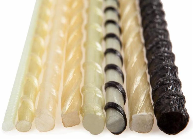 Przekrój poprzeczny prętów kompozytowych o różnych kolorach i fakturach, od białego po czarny, na białym tle.