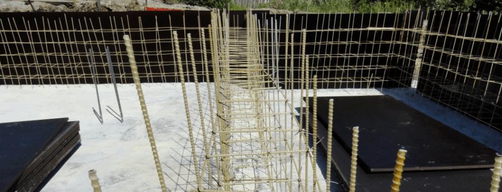 Siatka zbrojeniowa ułożona w wykopie fundamentowym, widoczne szalunki i wystające pręty.