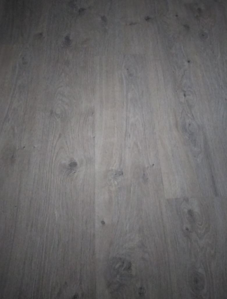 Ułożone panele podłogowe w odcieniach szarości z widoczną strukturą drewna. Delikatna tekstura i matowe wykończenie.