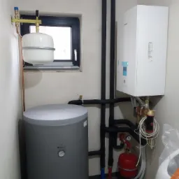 Kotłownia z zamontowanym zasobnikiem Galmet, pompą ciepła Panasonic, naczyniem przeponowym i instalacją hydrauliczną z rur miedzianych oraz czarnych rur izolowanych.