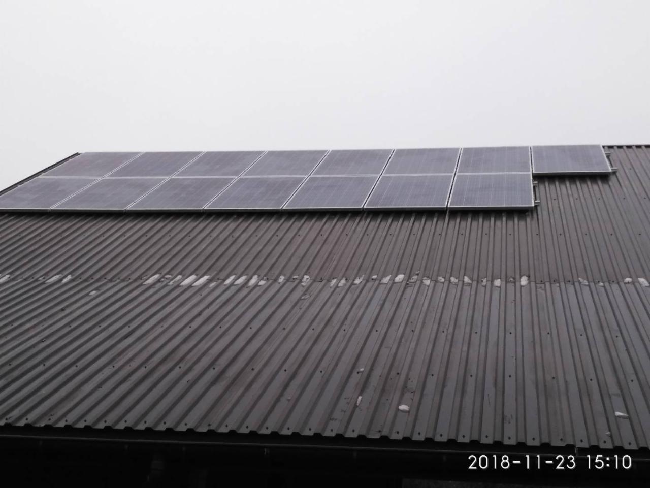 Panele słoneczne na blaszanym dachu w Czarnej, widoczne z dołu pod kątem, pochmurne niebo.