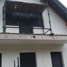 WORK-JAW - Budynek w trakcie budowy z rusztowaniem i zamontowanymi roletami okiennymi. Widoczne narzędzia na podeście.