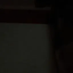 Słabo oświetlony fragment ściany z widocznym zarysem sufitu i elementami w ciemnych odcieniach.