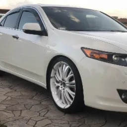 Biała Honda Accord na tle kostki brukowej, z wyraźnie widocznymi felgami o unikalnym wzorze i czerwonymi zaciskami hamulcowymi.