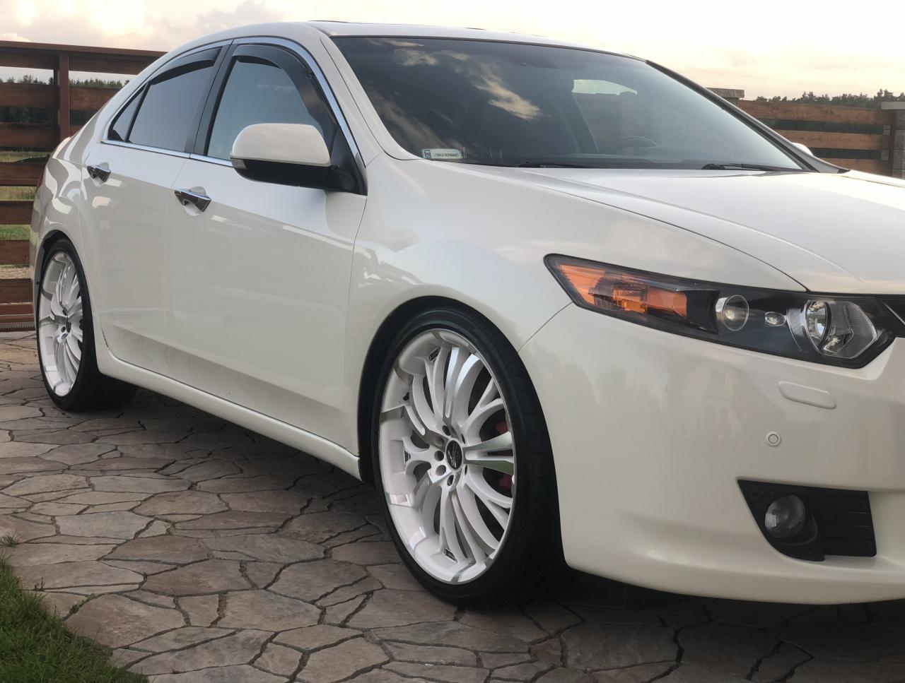 Biała Honda Accord na tle kostki brukowej, z wyraźnie widocznymi felgami o unikalnym wzorze i czerwonymi zaciskami hamulcowymi.