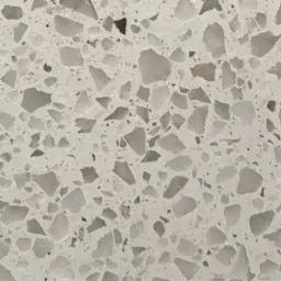 Jasna, polerowana powierzchnia terazzo z nieregularnymi, szarymi i białymi kamieniami o różnej wielkości.