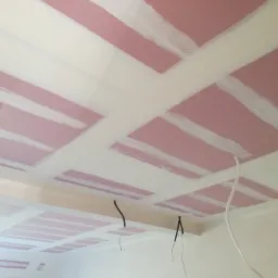 Różowe płyty kartonowo-gipsowe na suficie, wzmocnione białą siatką, widoczne kable elektryczne zwisające z sufitu.