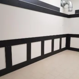 Pusta, czysta ściana w pomieszczeniu biurowym z czarnymi listwami ochronnymi na dole i górze, oraz wentylacja pod sufitem.