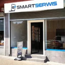 Fasada serwisu telefon&oacute;w SmartSerwis z logo przedstawiającym telefon z kołem zębatym, tablica reklamowa z napisem 'Do każdej naprawy dowolne etui gratis', widok na wnętrze z akcesoriami...