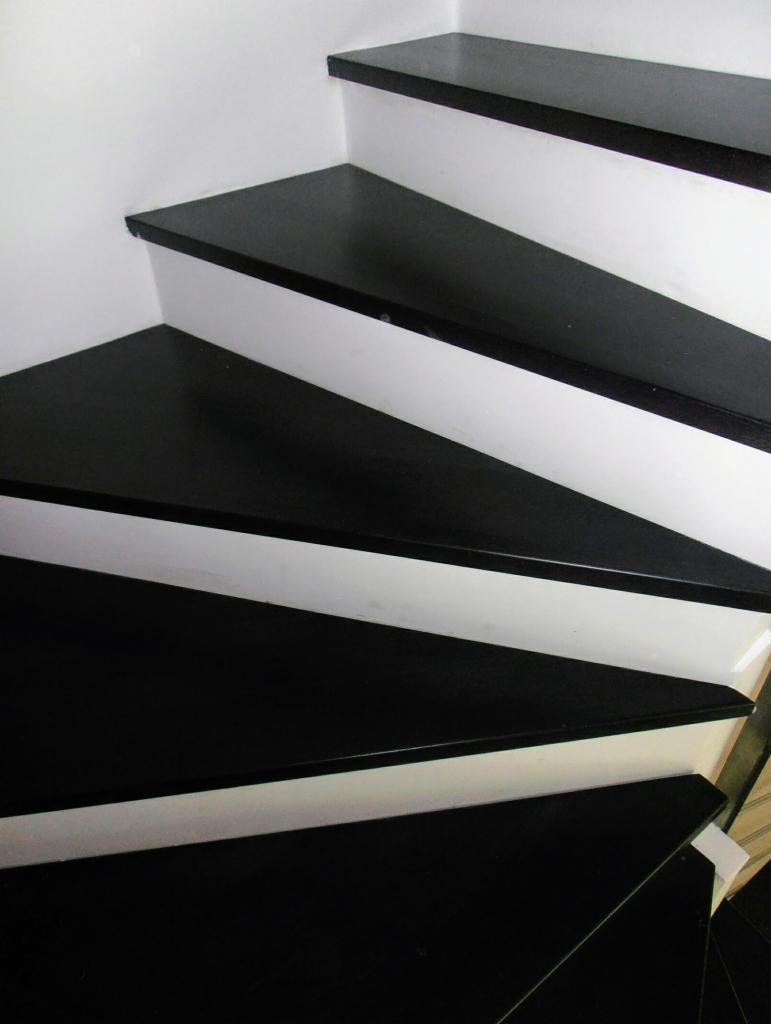 Nowoczesne schody z czarnymi stopniami i białymi podstopnicami, widok z góry, minimalistyczny design.