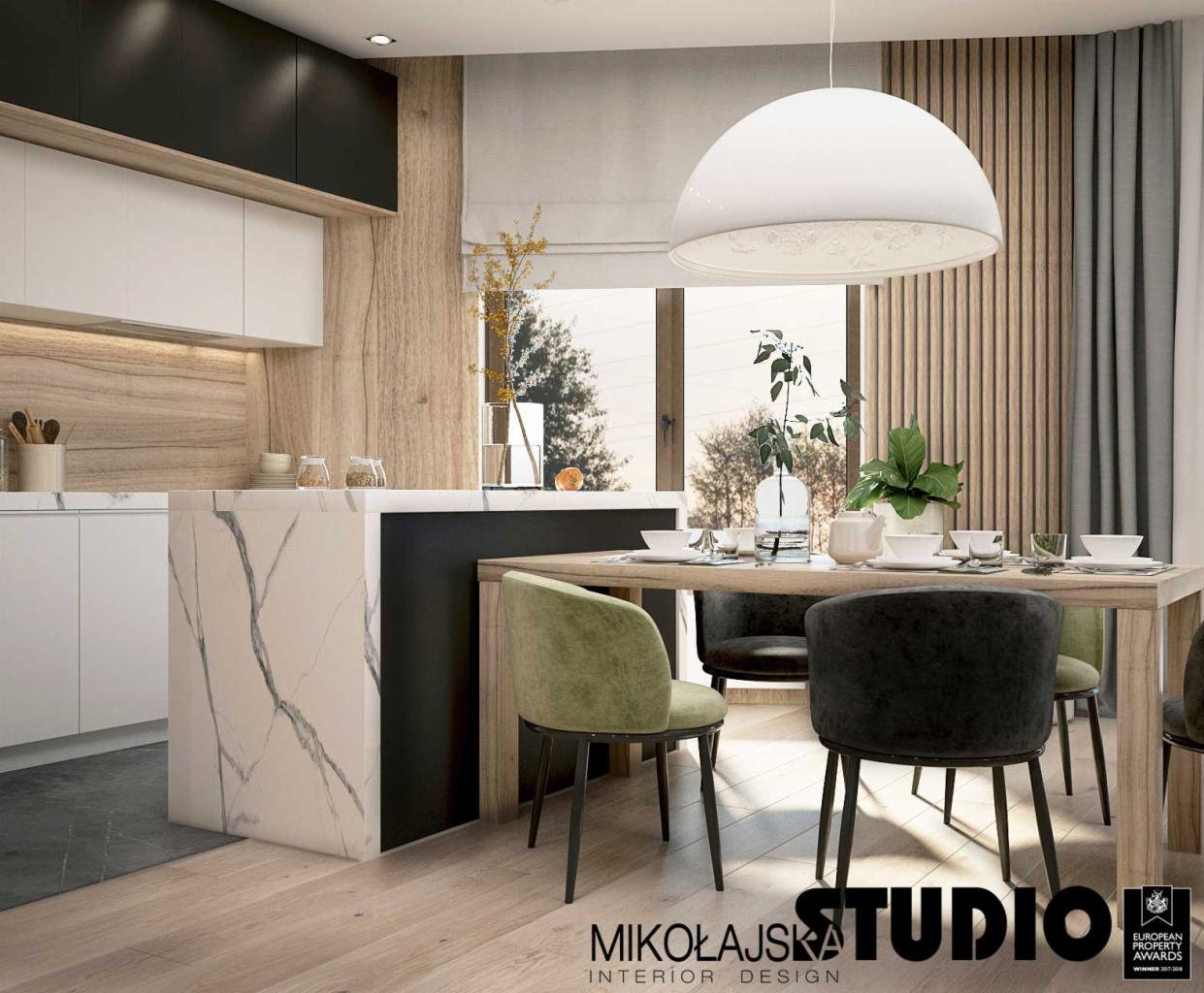 Wizualizacja jadalni z aneksem kuchennym, drewniane panele na ścianie, stół z krzesłami w odcieniach zieleni i szarości, wyspa kuchenna z marmurowym wykończeniem, nowoczesna lampa wisząca.