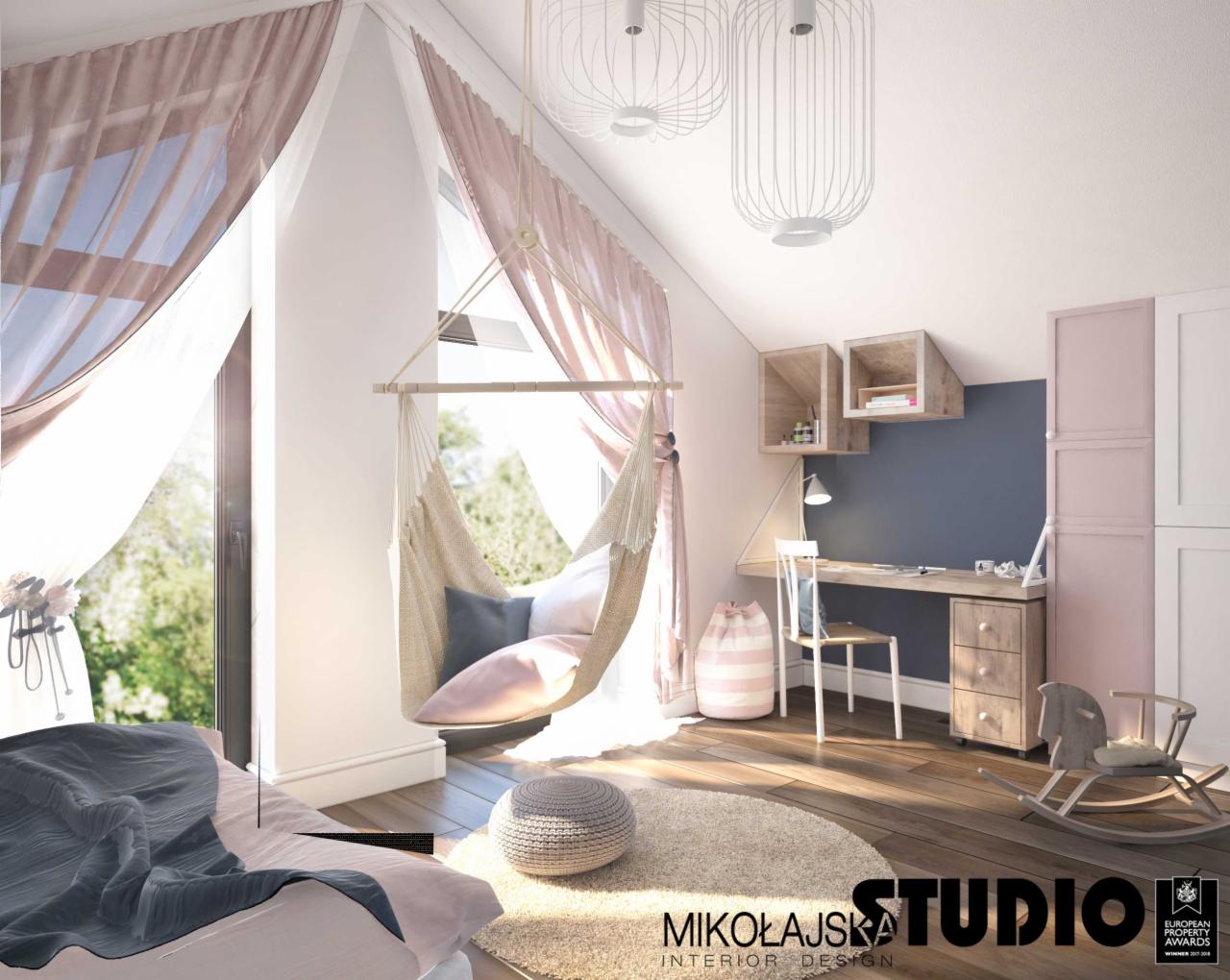Pokój dziecięcy na poddaszu z hamakiem brazylijskim przy oknie, biurkiem z półkami, konikiem na biegunach i lampami w stylu skandynawskim.