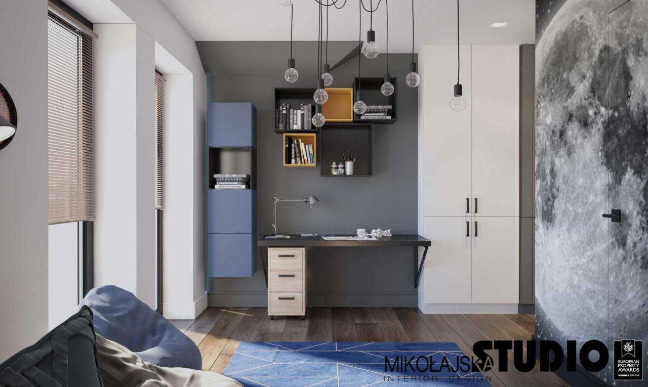 Pokój młodzieżowy z biurkiem, regałami w kolorach niebieskim i żółtym oraz fototapetą z motywem księżyca na drzwiach.