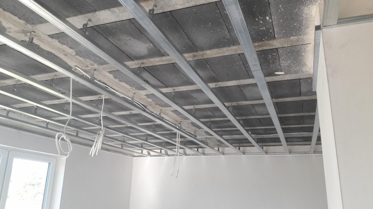 Metalowa konstrukcja sufitu podwieszanego z widocznymi bloczkami betonowymi w Jeleniej Górze, przygotowana pod montaż płyt gipsowo-kartonowych, z wiszącymi przewodami elektrycznymi.