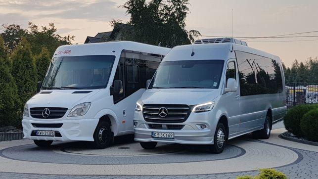 Dwa busy Mercedes-Benz Sprinter: biały starszy model z napisem SX-BUS i srebrny nowszy model z klimatyzacją dachową, stojące na ozdobnym podjeździe z kostki.