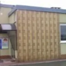 Budynek firmy z Jeleniej Góry z charakterystyczną, pionową okładziną elewacyjną w odcieniach beżu i brązu, widoczne wejście z daszkiem i tablicą informacyjną.