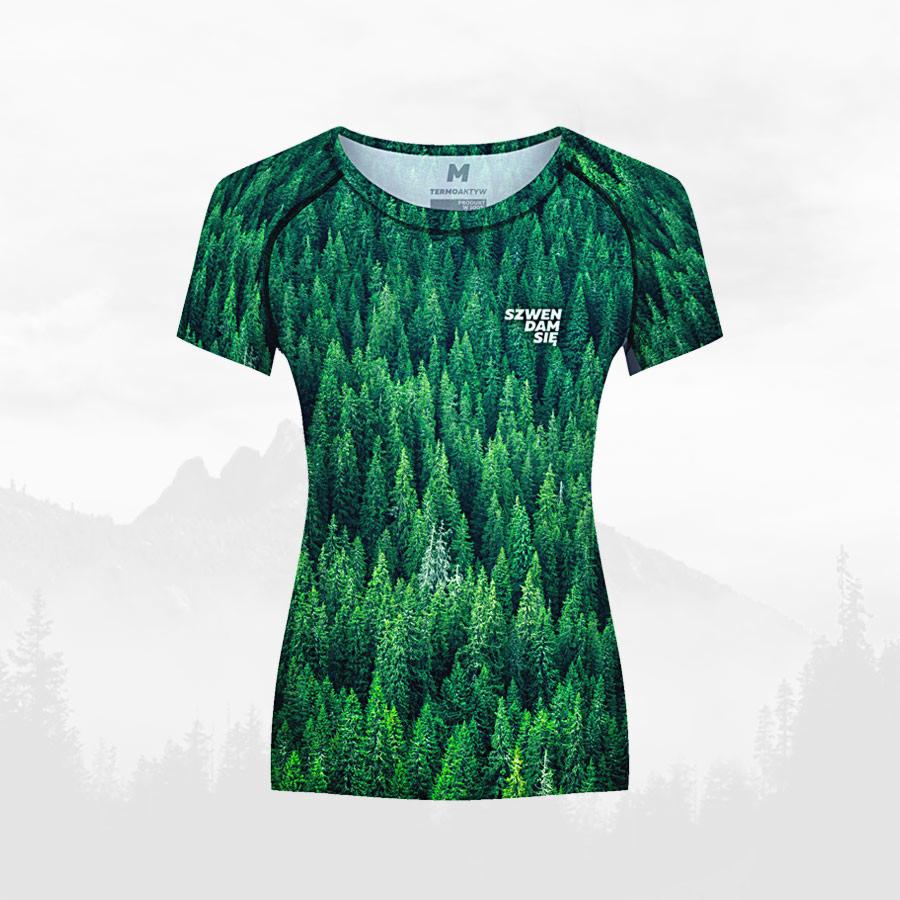 Damska koszulka termoaktywna z nadrukiem gęstego lasu iglastego na tle górskiej panoramy.