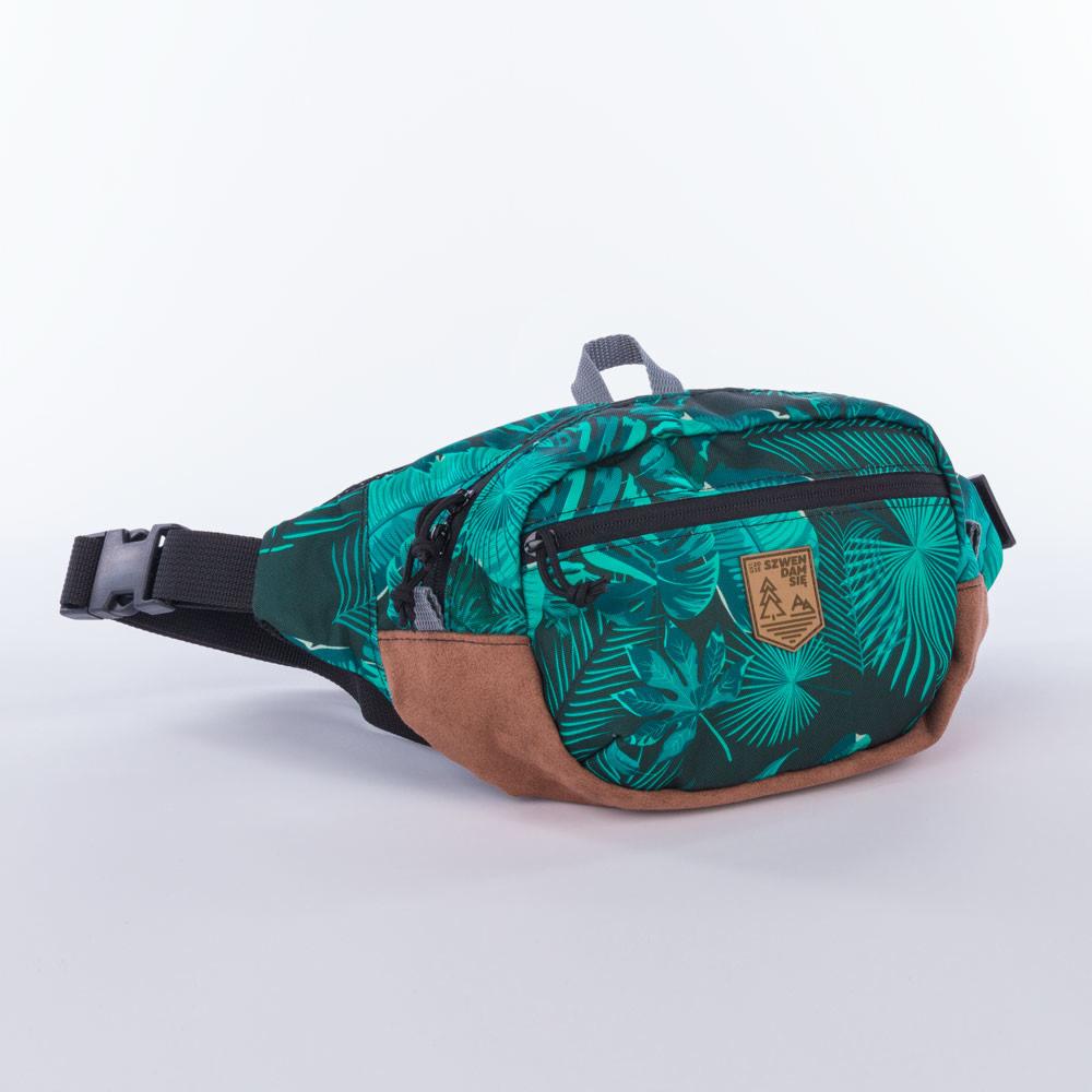Saszetka biodrowa typu nerka z tropikalnym wzorem liści palmowych, brązowym spodem i czarnymi zamkami błyskawicznymi, leżąca na białym tle.