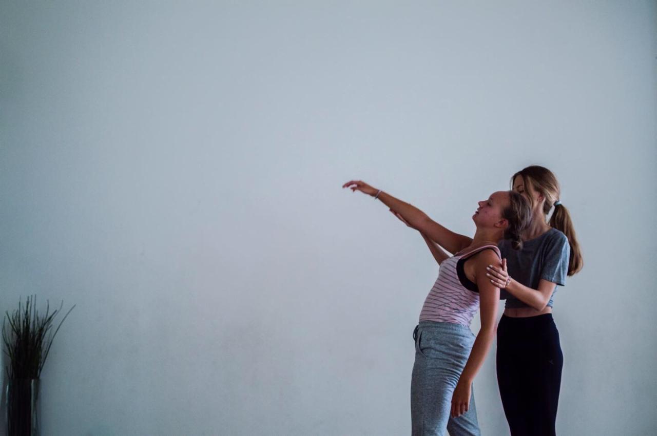 Instruktorka koryguje postawę uczennicy podczas zajęć tanecznych w jasnym studiu.