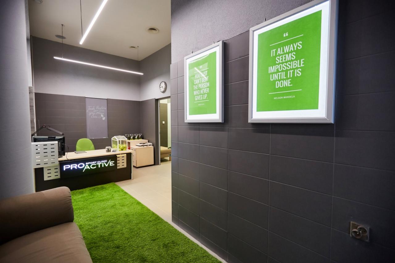 Wnętrze gabinetu z recepcją, zielonym dywanem imitującym trawę i motywującymi plakatami na ścianach w odcieniach szarości.