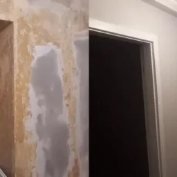 Remont korytarza w Lubinie: porównanie stanu przed i po wygładzeniu i pomalowaniu ścian na jasny kolor, widoczne gładzie i nowe ościeżnice.