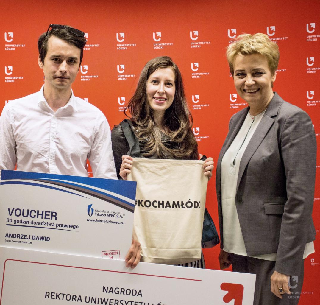 Trzy osoby pozują do zdjęcia z voucherem na 30 godzin doradztwa prawnego i torbą z napisem #KOCHAMŁÓDŹ na tle ściany z logo Uniwersytetu Łódzkiego.