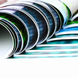 Stos katalogów z widocznymi kolorowymi stronami wewnętrznymi, ułożonych kaskadowo.