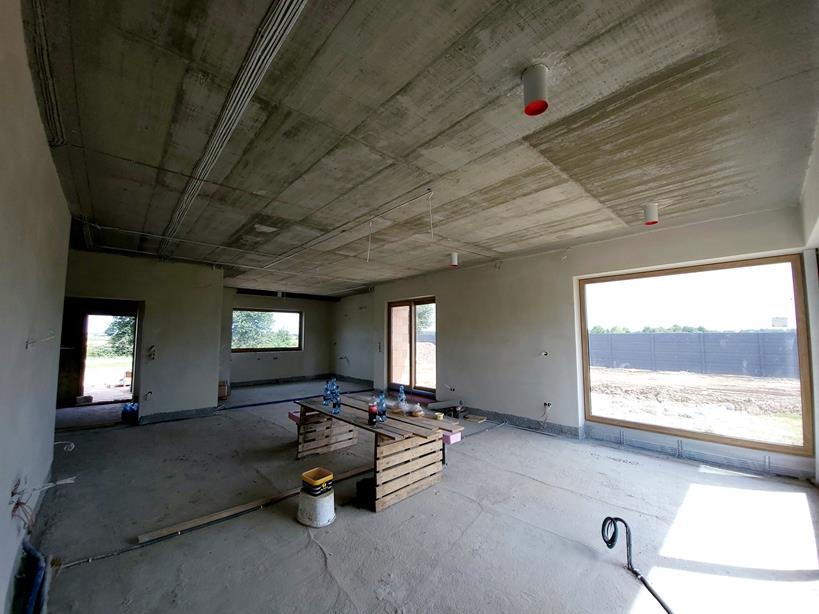 Surowy stan wnętrza domu jednorodzinnego z widoczną instalacją elektryczną pod sufitem, przygotowany do montażu wentylacji mechanicznej z odzyskiem ciepła.