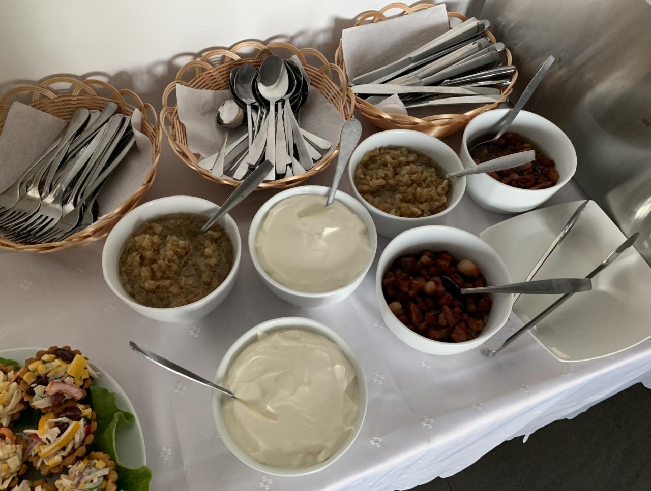 Bufet z przystawkami: tartaletki, sosy w miseczkach, sztućce w koszykach z wikliny, na białym obrusie.