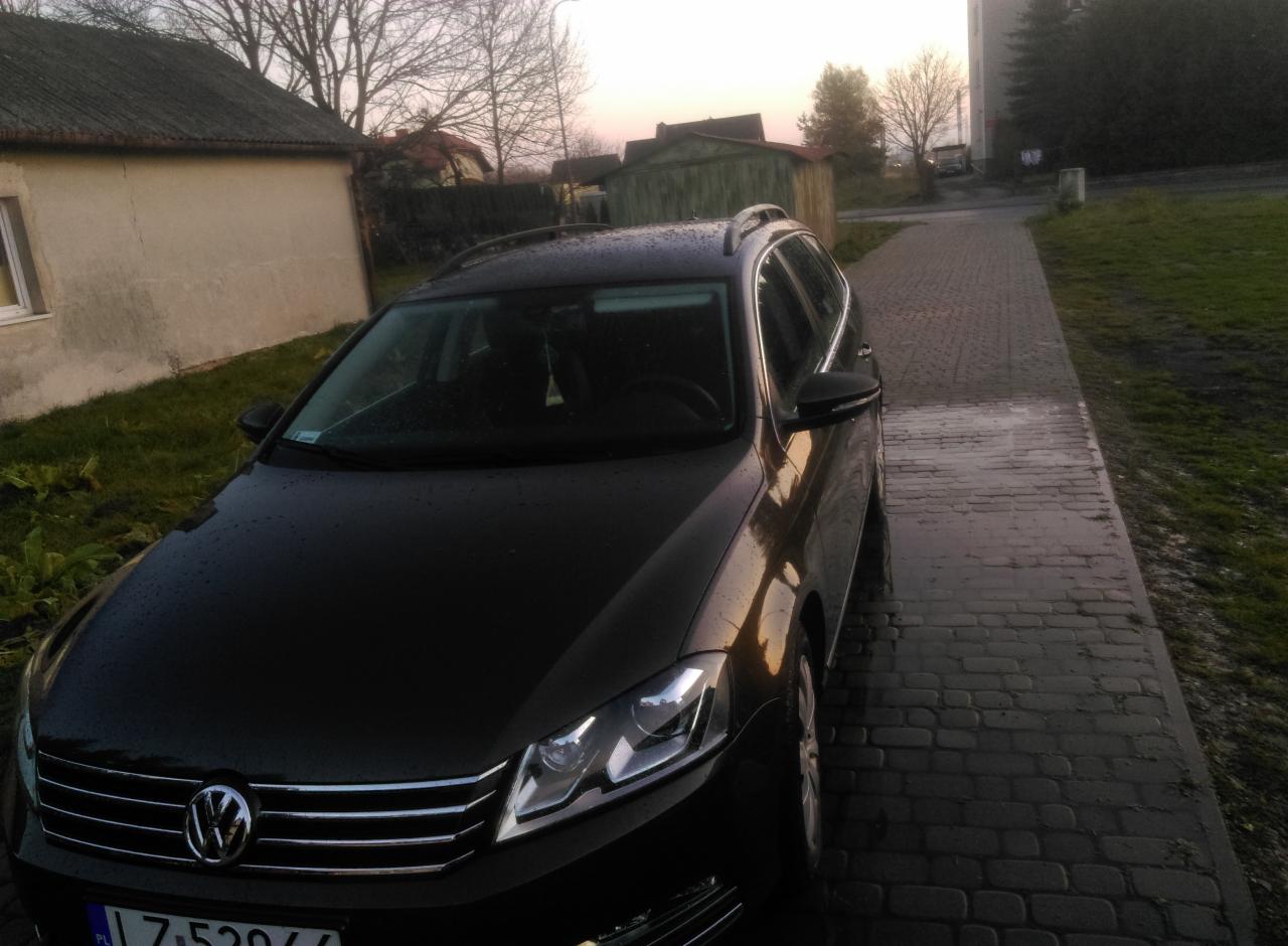 Czarny samochód kombi Volkswagen zaparkowany na brukowanej drodze w pobliżu budynku w pochmurny dzień.