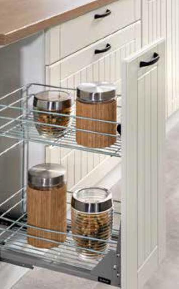 Wysuwana, druciana półka w szafce kuchennej z jasnymi, frezowanymi frontami, na której stoją cztery szklane słoiki z bambusowymi obudowami i metalowymi pokrywkami, częściowo wypełnione przyprawami.